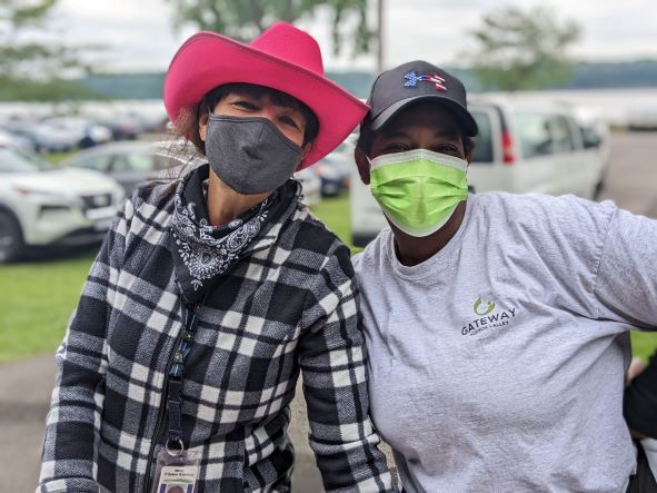 Two women in masks. One in a pink cowboy hat.