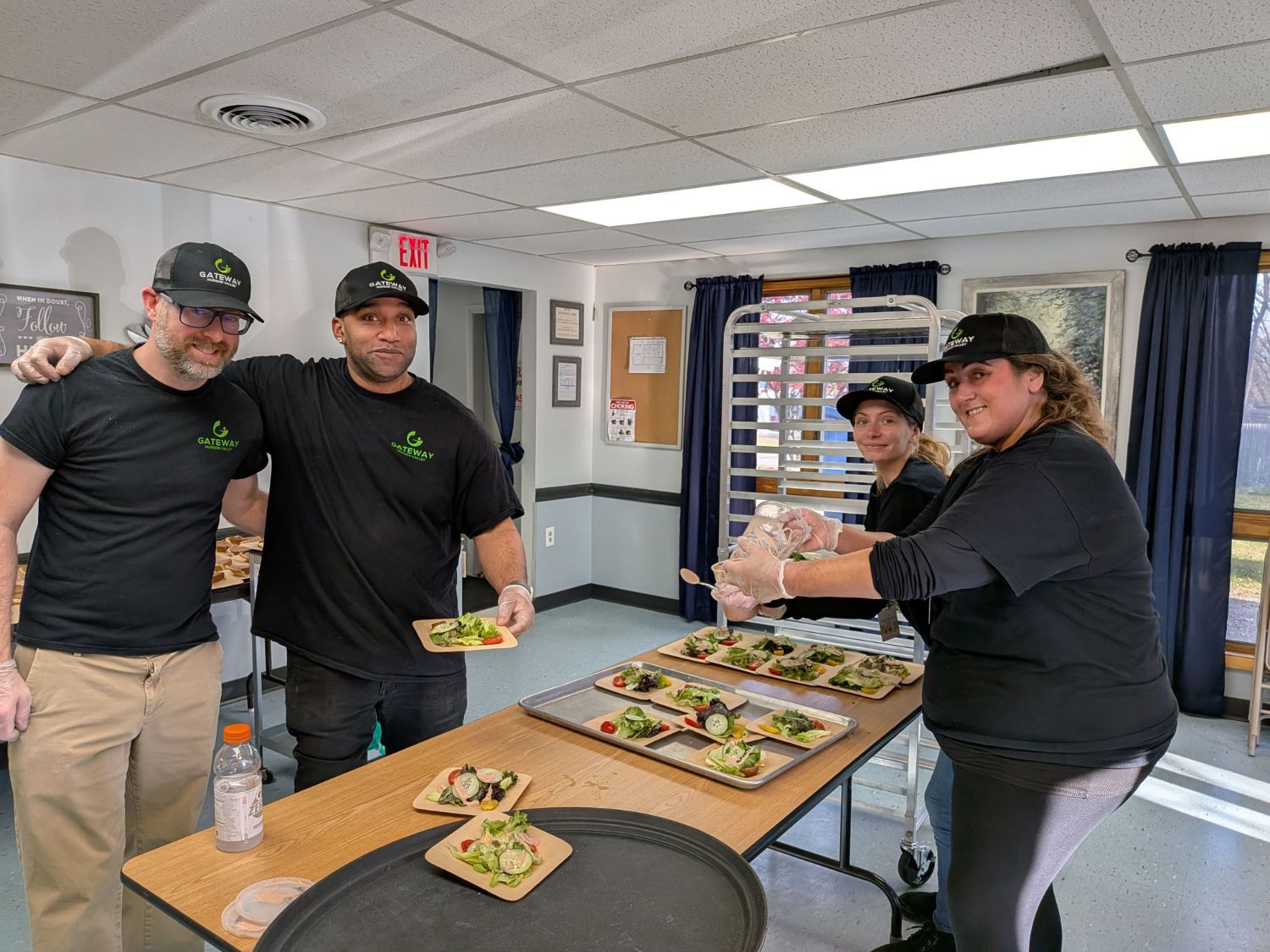 Staff preparing a large quantity of meals in a kitchen while laughing and having fun