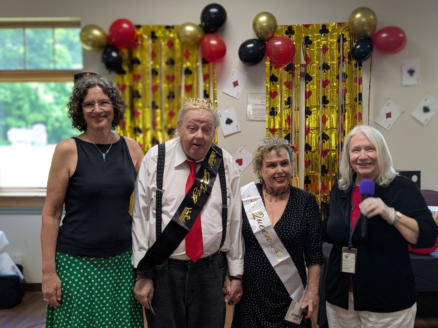4 people posing together. The older man and woman in the middle have been crowned king and queen of the dance.