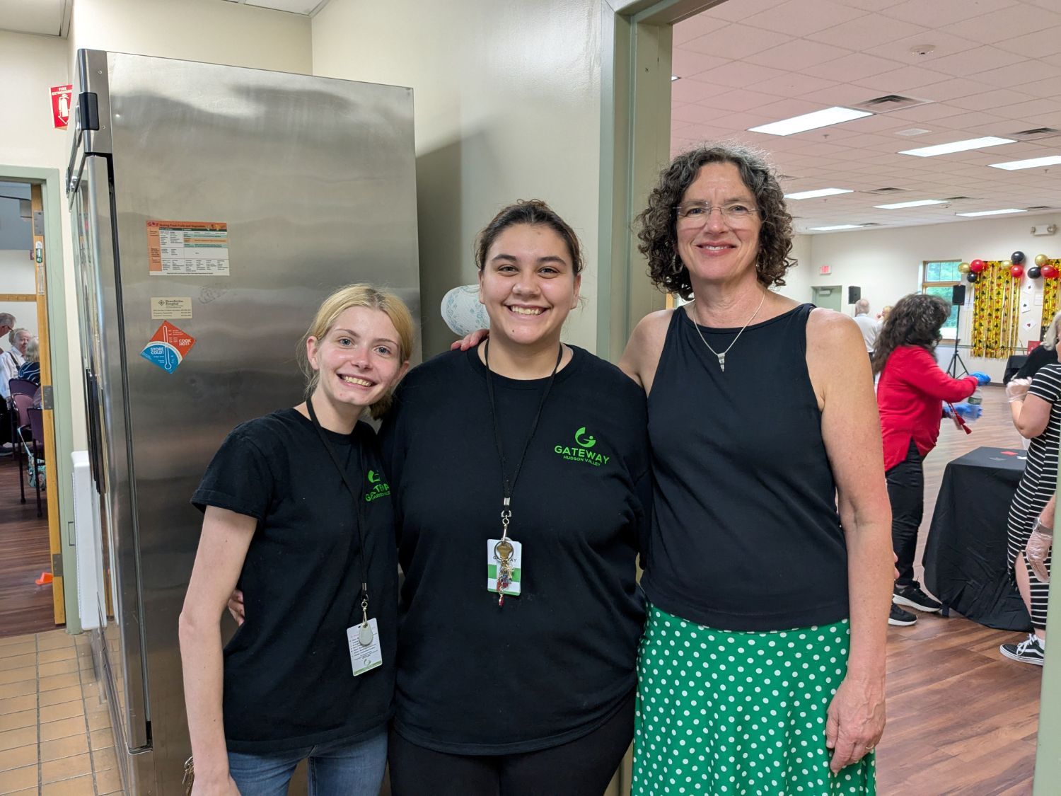Three women arm in arm posing for the picture in a commercial kitchen