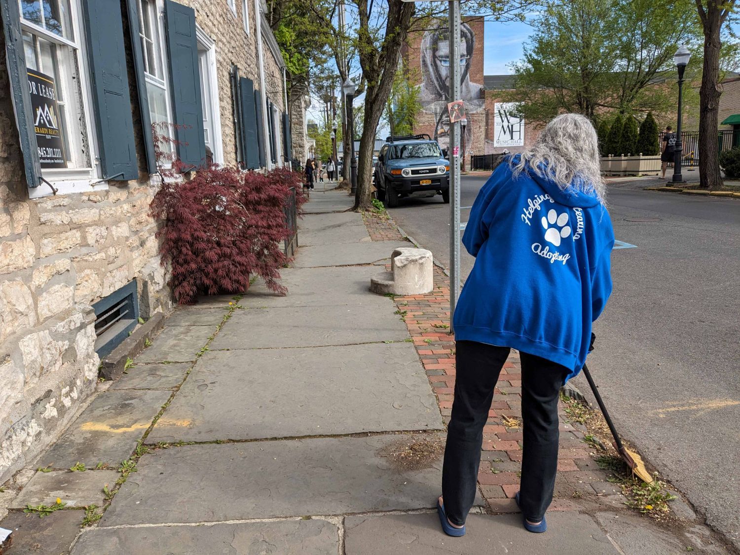 Lady sweeping a sidewalk