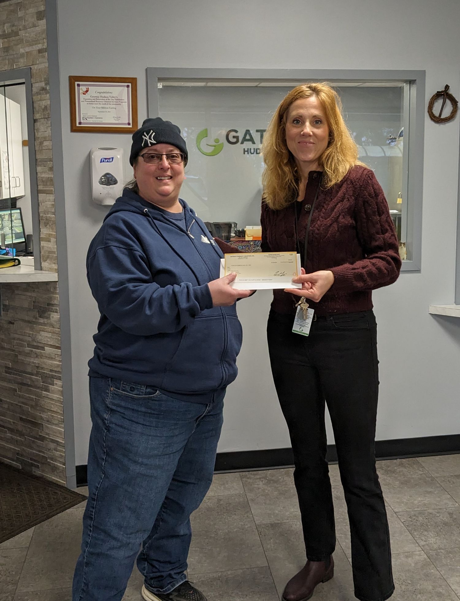 Two women holding a check in between each other smiling