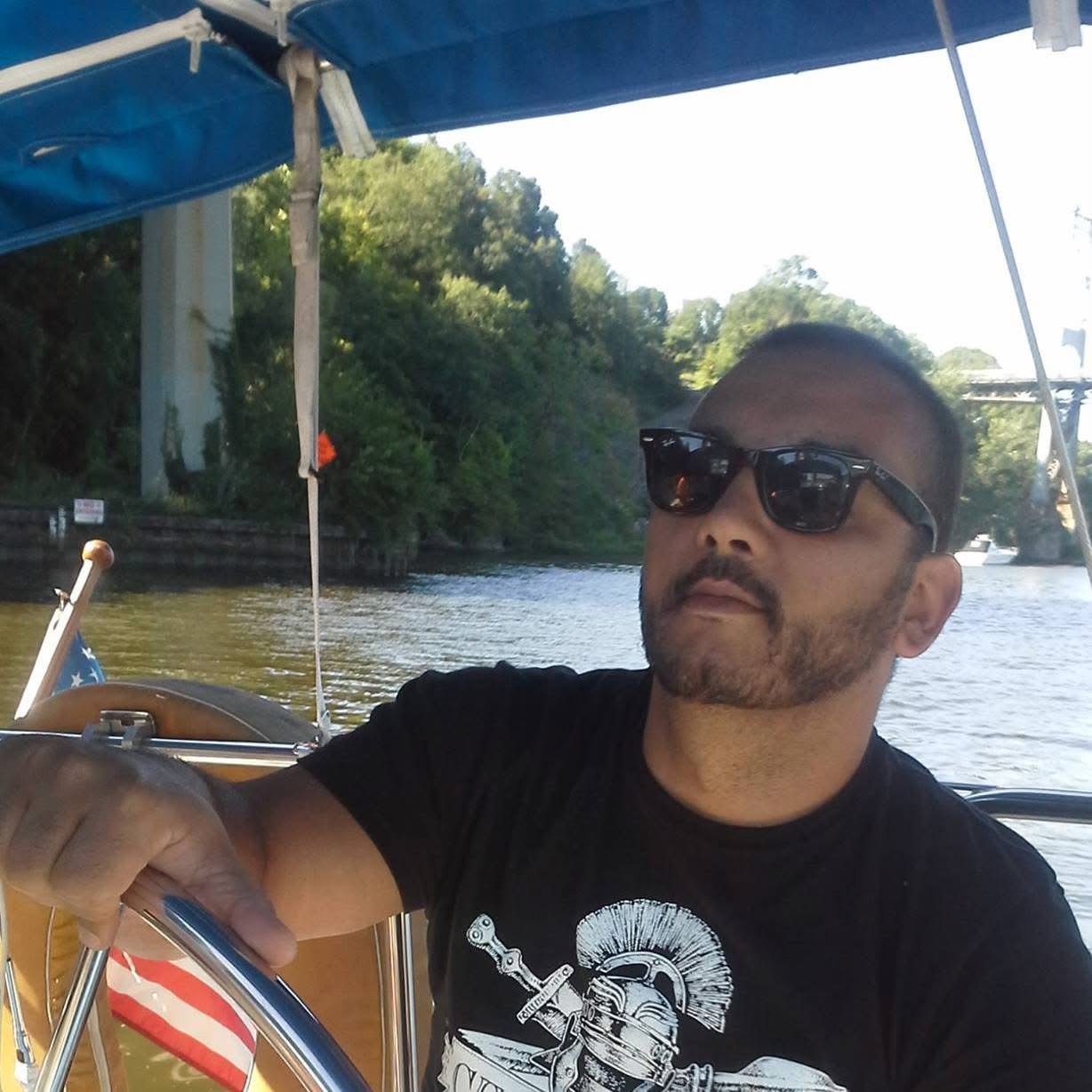 Mark steering a boat with sunglasses on